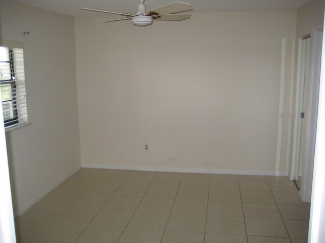 empty room with light tile patterned floors, baseboards, and a ceiling fan