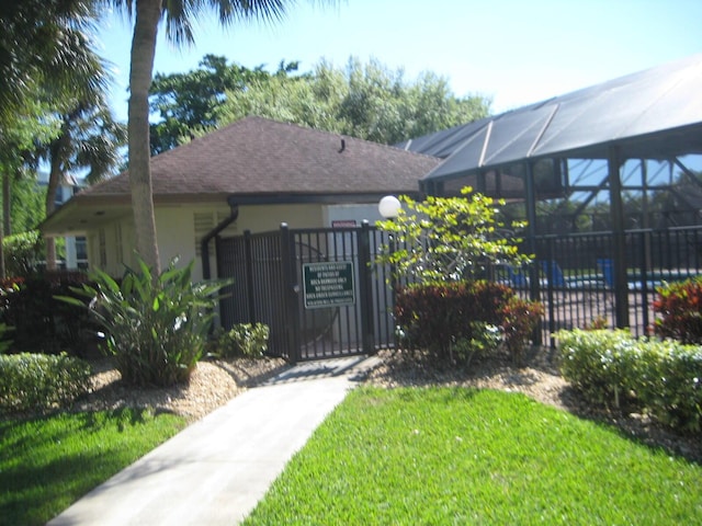 view of front facade with a gate, stucco siding, a lanai, and fence