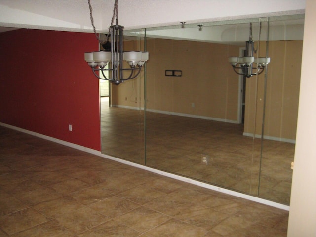 unfurnished dining area featuring baseboards and a chandelier