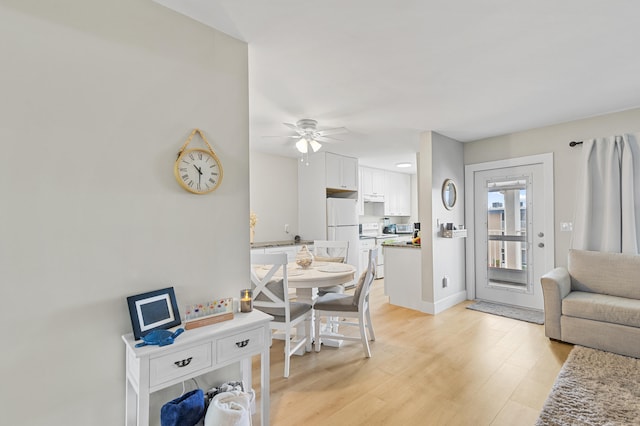 dining space featuring light wood finished floors, a ceiling fan, and baseboards