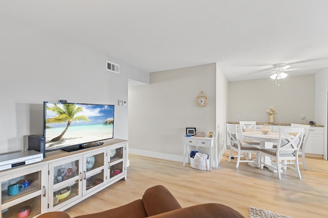 living room with a ceiling fan, baseboards, visible vents, and light wood finished floors