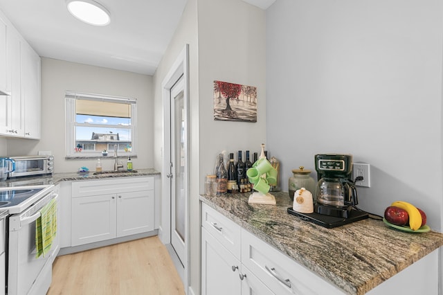 kitchen featuring white electric stove, a toaster, a sink, and white cabinets