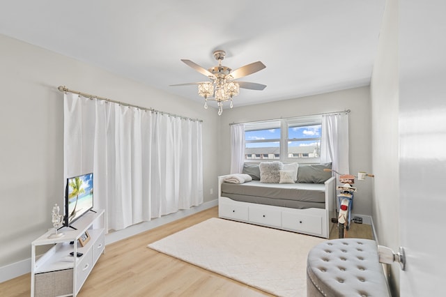 living area featuring ceiling fan, baseboards, and wood finished floors