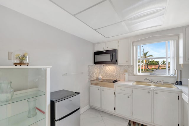 kitchen featuring marble finish floor, backsplash, white cabinets, a sink, and black appliances