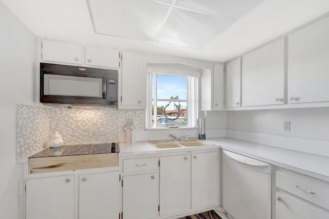 kitchen with black microwave, white dishwasher, a sink, white cabinets, and decorative backsplash