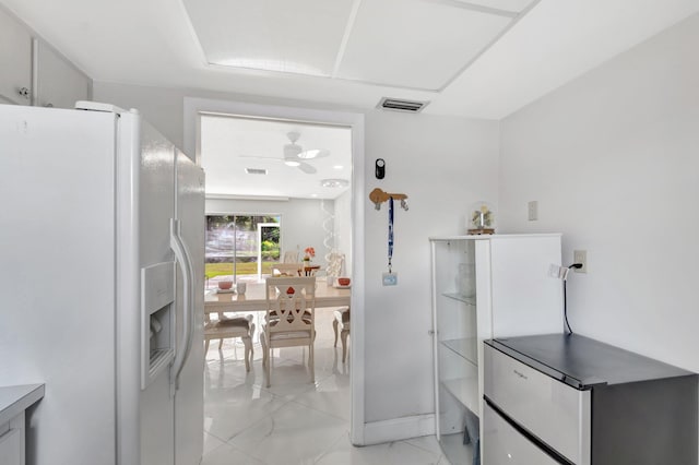 kitchen with marble finish floor, white fridge with ice dispenser, ceiling fan, and visible vents