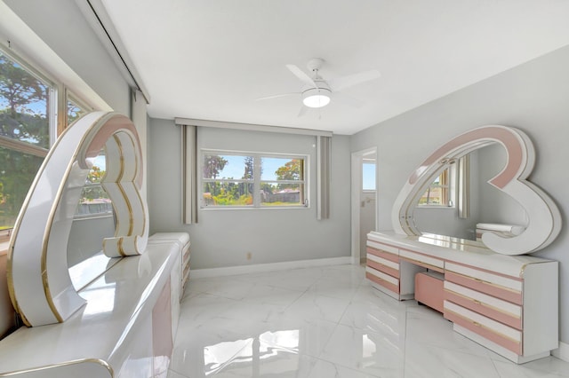 interior space featuring marble finish floor, ceiling fan, and baseboards