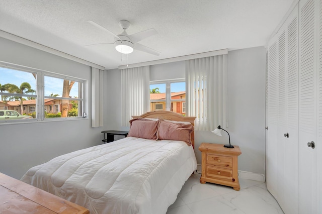 bedroom featuring a closet, marble finish floor, ceiling fan, and a textured ceiling