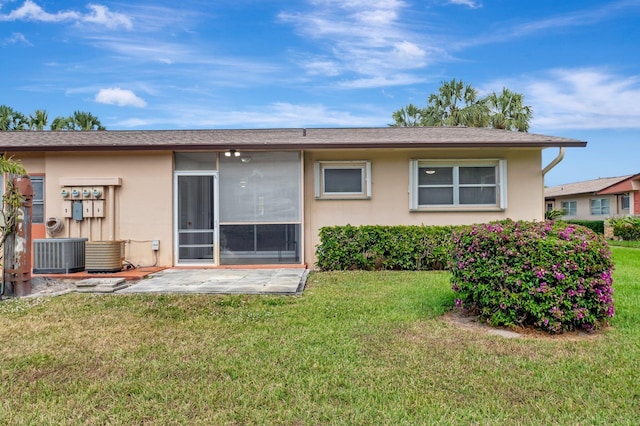 back of property with a patio, a lawn, central AC unit, and stucco siding