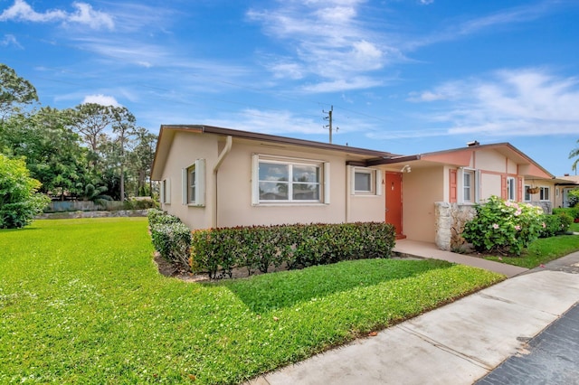 ranch-style house with a front lawn and stucco siding