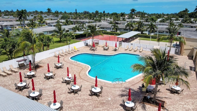 community pool featuring a patio area, a fenced backyard, and a residential view