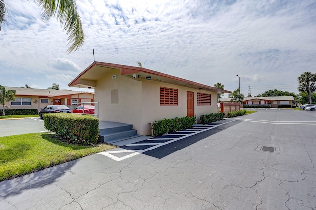 view of property exterior with uncovered parking and stucco siding