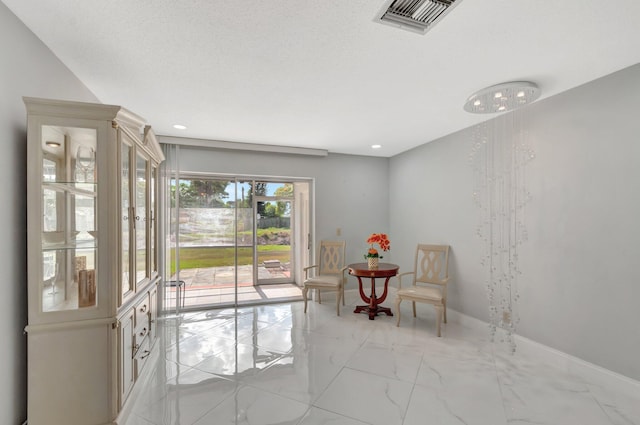 sitting room with a textured ceiling, marble finish floor, visible vents, and baseboards