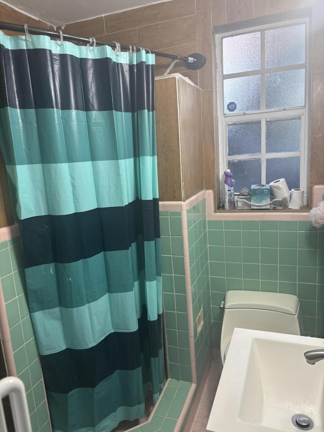 full bath featuring toilet, tile walls, a sink, and a shower with shower curtain