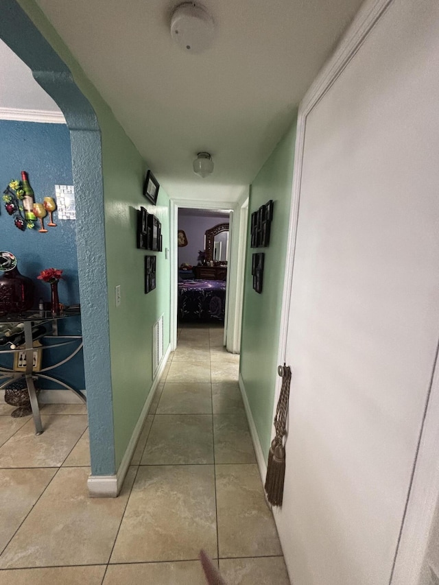 hallway with baseboards, visible vents, and light tile patterned flooring