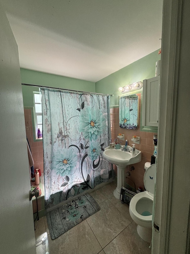 bathroom featuring shower / tub combo, toilet, a wainscoted wall, tile patterned floors, and tile walls