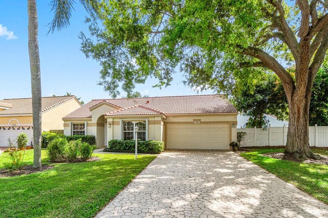 mediterranean / spanish house featuring a garage, a tile roof, fence, decorative driveway, and a front lawn