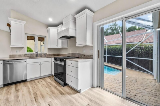 kitchen featuring white cabinets, light wood-style flooring, appliances with stainless steel finishes, and a sink