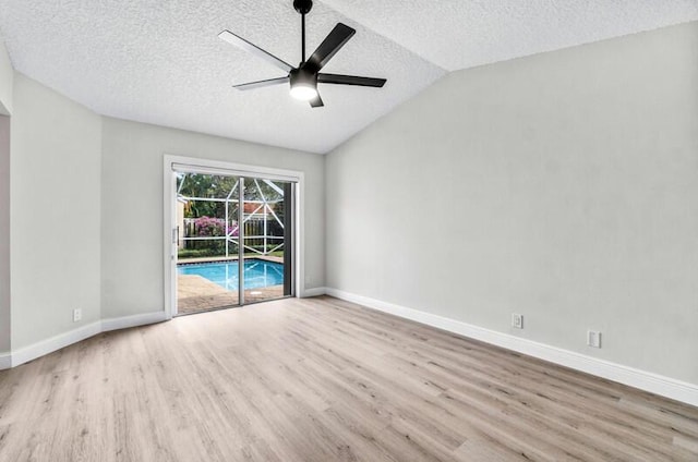 spare room with a ceiling fan, wood finished floors, baseboards, lofted ceiling, and a textured ceiling