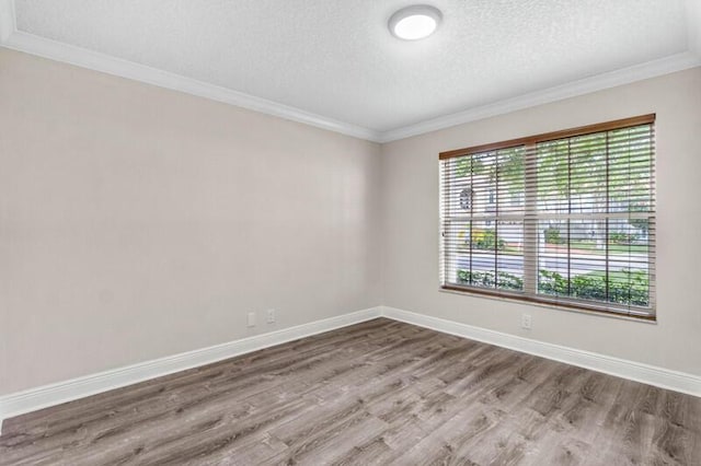 unfurnished room with ornamental molding, wood finished floors, baseboards, and a textured ceiling