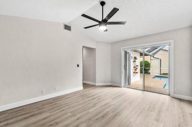 empty room with visible vents, a ceiling fan, wood finished floors, baseboards, and vaulted ceiling