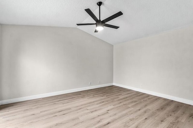 empty room with wood finished floors, baseboards, ceiling fan, vaulted ceiling, and a textured ceiling