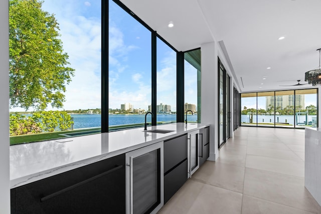 kitchen featuring floor to ceiling windows, a water view, modern cabinets, beverage cooler, and dark cabinetry