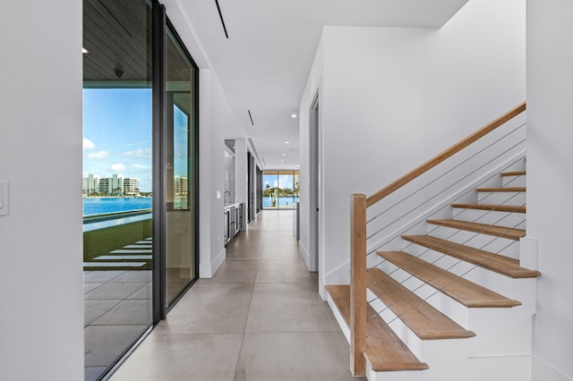 corridor featuring expansive windows, recessed lighting, baseboards, and stairs