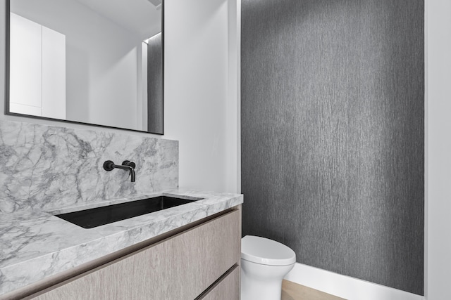 bathroom with backsplash, toilet, and vanity