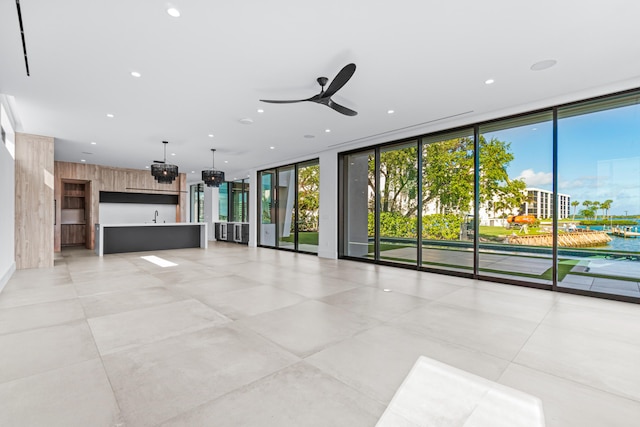 unfurnished living room with ceiling fan, a wall of windows, a sink, and recessed lighting