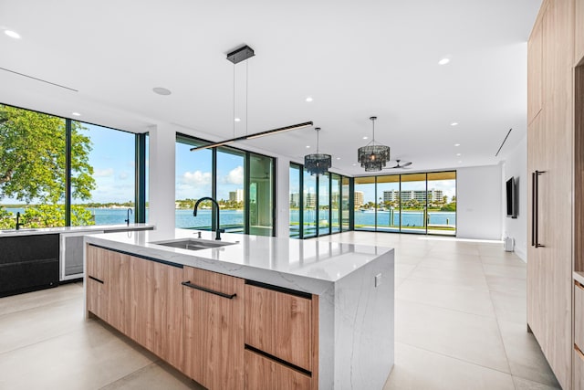 kitchen featuring a large island, modern cabinets, light stone counters, open floor plan, and a sink