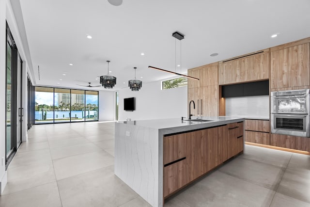 kitchen featuring double oven, a sink, a large island, floor to ceiling windows, and modern cabinets