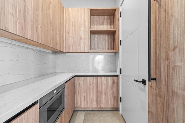 kitchen featuring light stone counters, stainless steel microwave, modern cabinets, and light brown cabinets