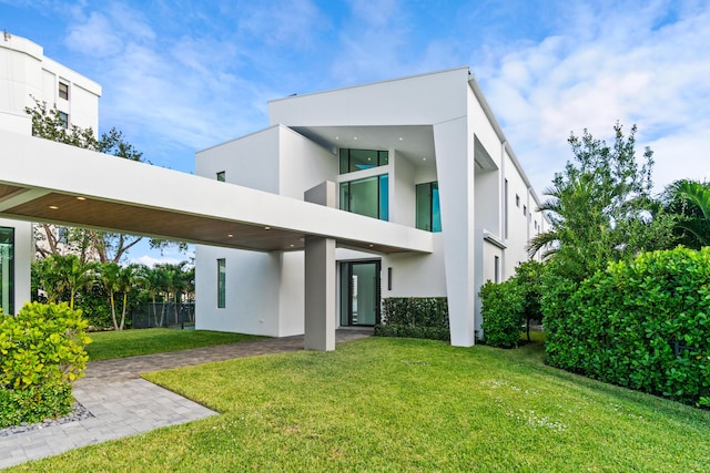 rear view of property featuring a lawn and stucco siding