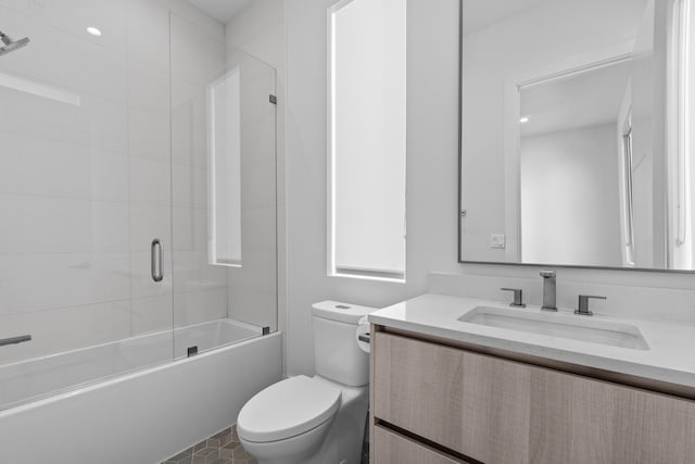 bathroom featuring enclosed tub / shower combo, vanity, and toilet