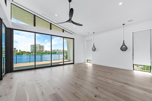 spare room with ceiling fan, a water view, vaulted ceiling, light wood-type flooring, and recessed lighting