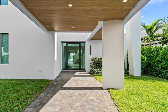 entrance to property with a lawn and stucco siding