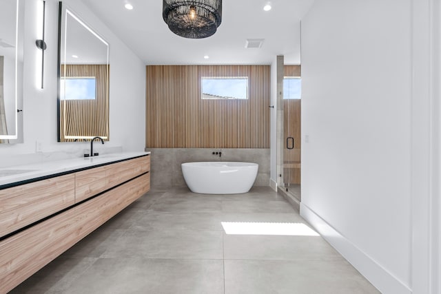 bathroom featuring double vanity, recessed lighting, a soaking tub, visible vents, and a sink