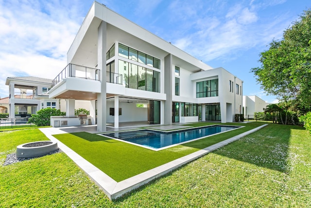 back of house featuring a patio, a yard, fence, a balcony, and an outdoor pool