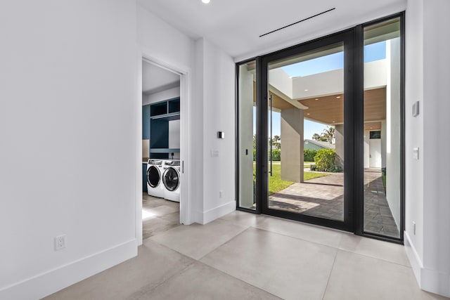 entrance foyer featuring baseboards, washer and clothes dryer, a wall of windows, and concrete flooring