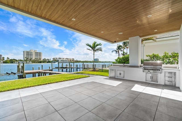 view of patio / terrace with boat lift, area for grilling, a water view, exterior kitchen, and a dock