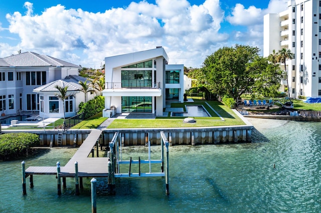 view of dock with a water view, a lawn, and a balcony