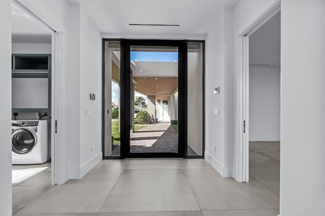 foyer entrance with expansive windows, washer / clothes dryer, concrete floors, and baseboards