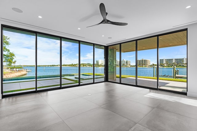 empty room with a wall of windows, a water view, and ceiling fan