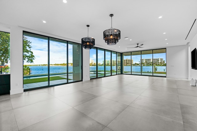 spare room featuring plenty of natural light, a wall of windows, a water view, and baseboards