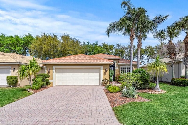 view of front of house with a tiled roof, a front yard, stucco siding, decorative driveway, and a garage