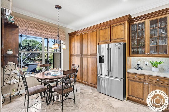 kitchen featuring brown cabinetry, glass insert cabinets, pendant lighting, crown molding, and stainless steel fridge