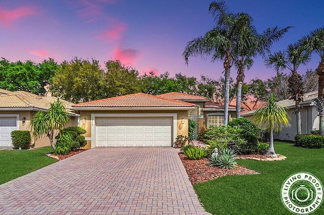 view of front of property with stucco siding, an attached garage, a lawn, and decorative driveway