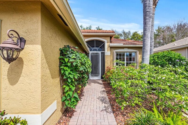 property entrance with stucco siding and a tile roof