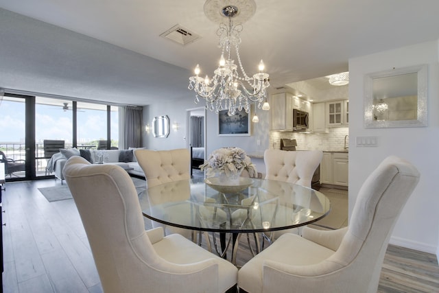 dining area with visible vents, expansive windows, an inviting chandelier, light wood finished floors, and baseboards